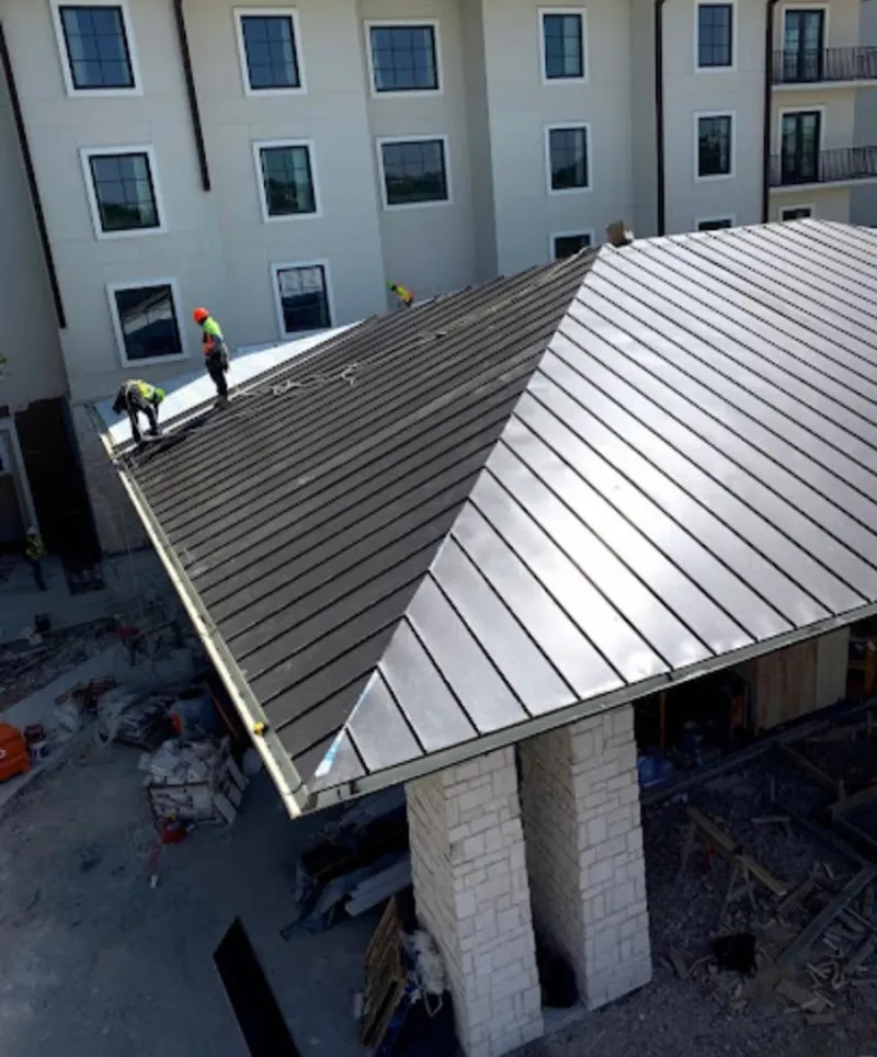 Crew installing standing seam metal roof panels on a commercial project in Allentown